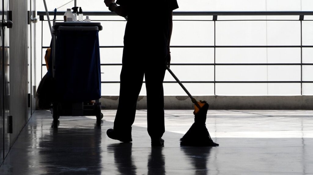 Colaboradora de uma prestadora de serviços terceirizados realizando a limpeza dos pisos de uma empresa. 