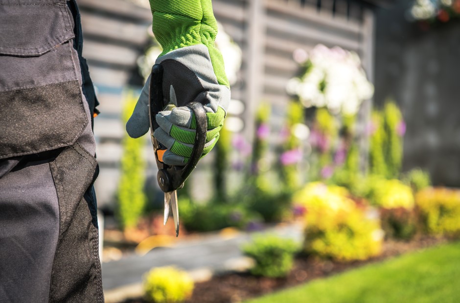 Profissional de uma organização de facilities realizando serviços pontuais para empresa na área dos jardins. 